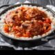 southern american country captain chicken fried and stewed with vegetables tomato sauce and curry served with rice in a frying pan on the table hor 2PH02NW Daily Global Diary - Authentic Global News