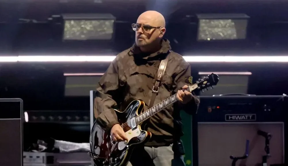 Paul “Bonehead” Arthurs, founding guitarist of Oasis, announced a temporary break from the band’s reunion tour to continue prostate cancer treatment, promising fans he’ll return “stronger than ever.”