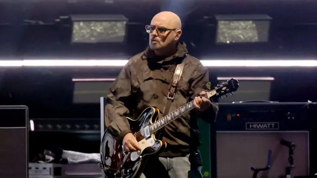 Paul “Bonehead” Arthurs, founding guitarist of Oasis, announced a temporary break from the band’s reunion tour to continue prostate cancer treatment, promising fans he’ll return “stronger than ever.”