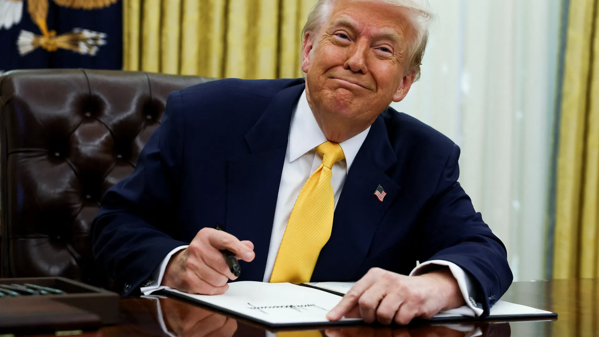 Former U.S. President Donald Trump signs pardon documents as part of a recent wave of clemency actions