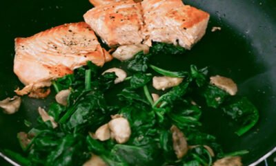 Woman Cooks Salmon With Spinach and Mushrooms