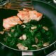 Woman Cooks Salmon With Spinach and Mushrooms
